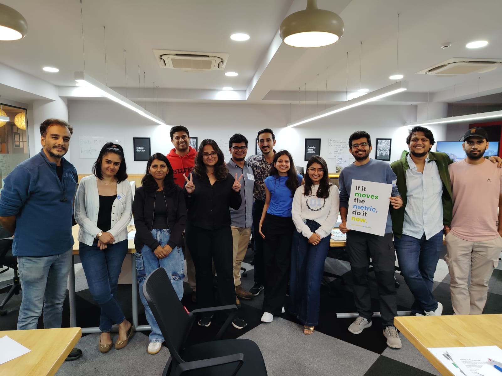 Shreya with her cohort in a Bengaluru office, one person holding a sign reading If it moves the metric, do it now